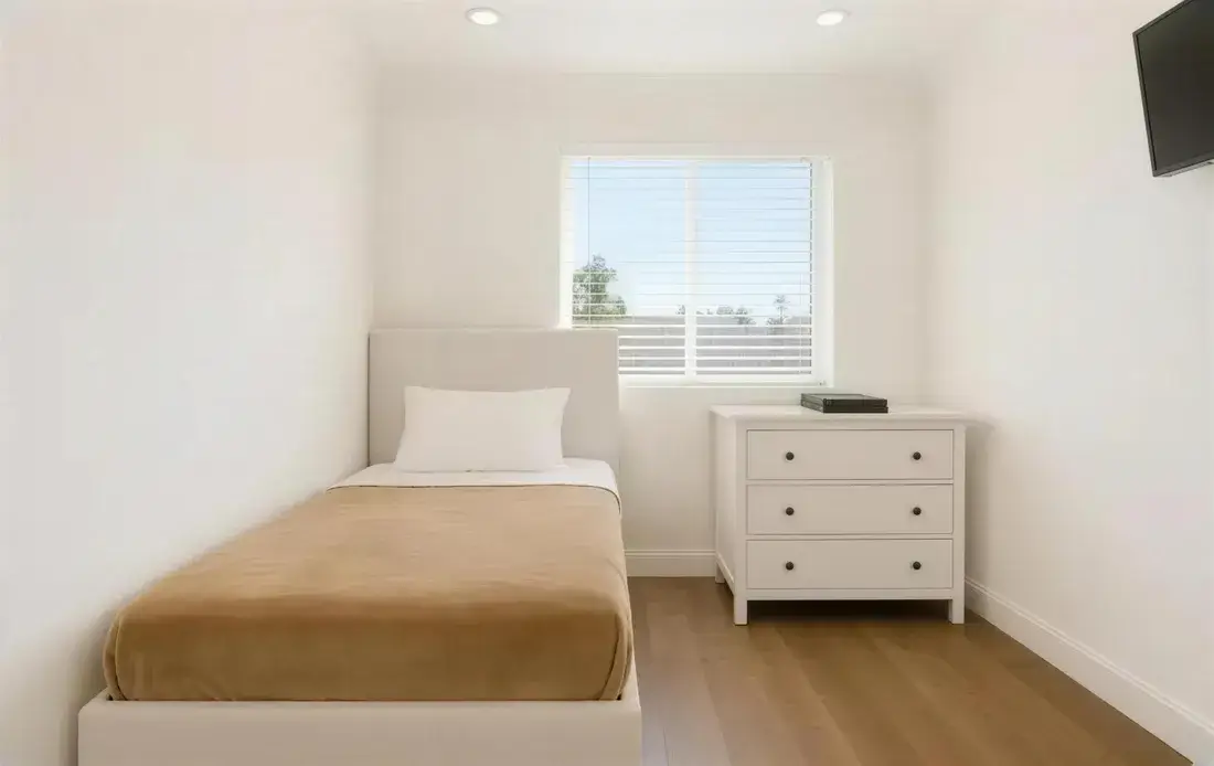 A made bed and dresser in a resident bedroom
